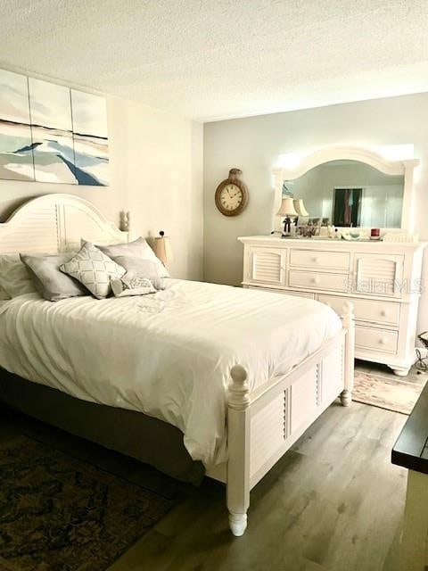 bedroom featuring a textured ceiling and dark hardwood / wood-style flooring