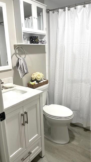 bathroom featuring toilet, hardwood / wood-style flooring, and vanity