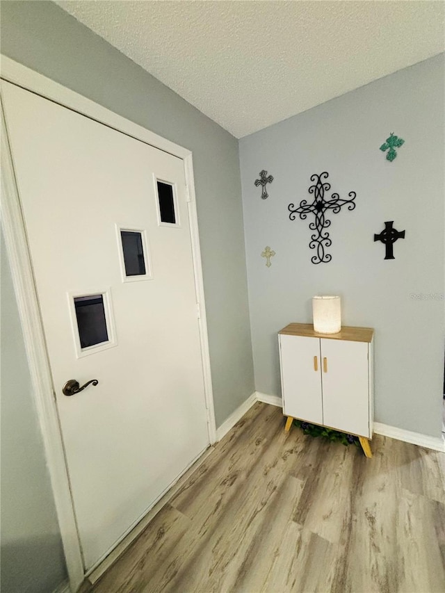 washroom with light hardwood / wood-style floors, a textured ceiling, and cabinets