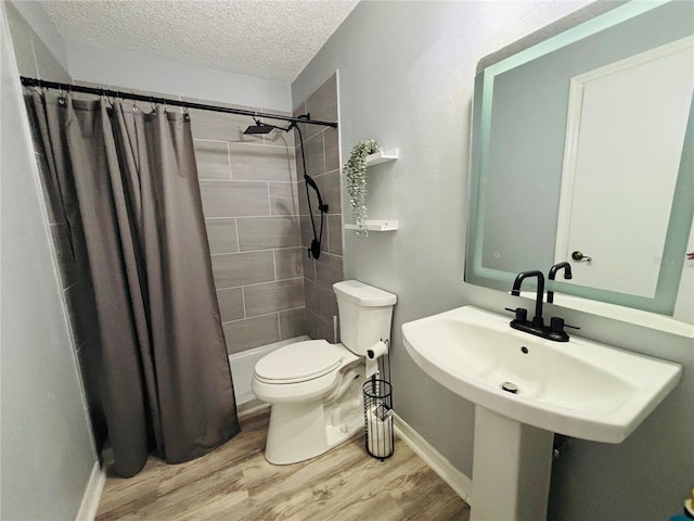 bathroom featuring hardwood / wood-style floors, a textured ceiling, toilet, and shower / bathtub combination with curtain