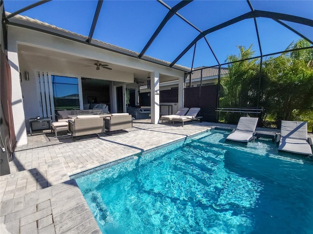 view of swimming pool with outdoor lounge area, a patio, glass enclosure, and ceiling fan