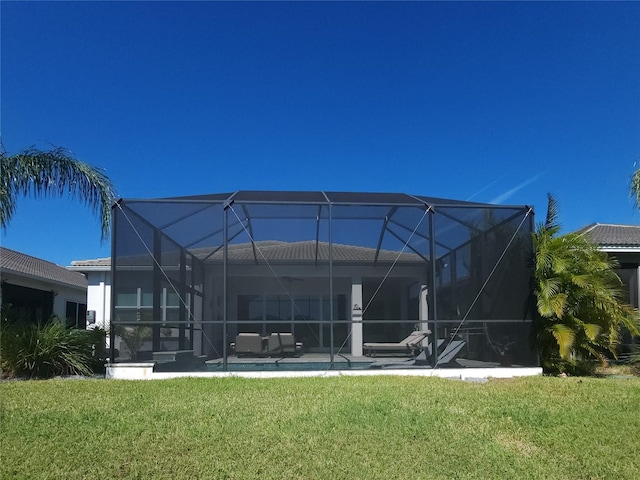 rear view of house with a yard, a patio area, and glass enclosure