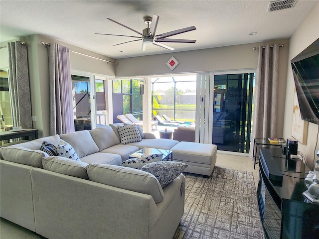 tiled living room with a textured ceiling and ceiling fan