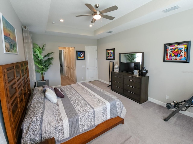 carpeted bedroom featuring a raised ceiling and ceiling fan