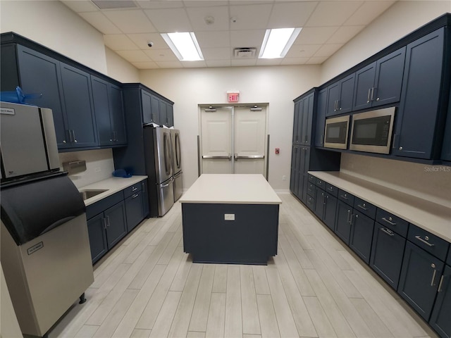 kitchen featuring a kitchen island, appliances with stainless steel finishes, a paneled ceiling, and light wood-type flooring