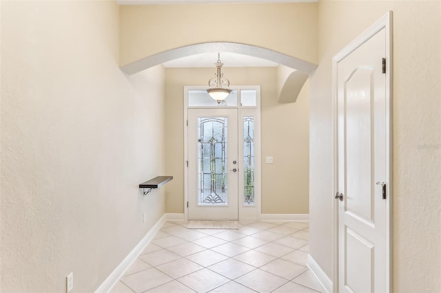 foyer featuring light tile patterned floors, baseboards, and arched walkways