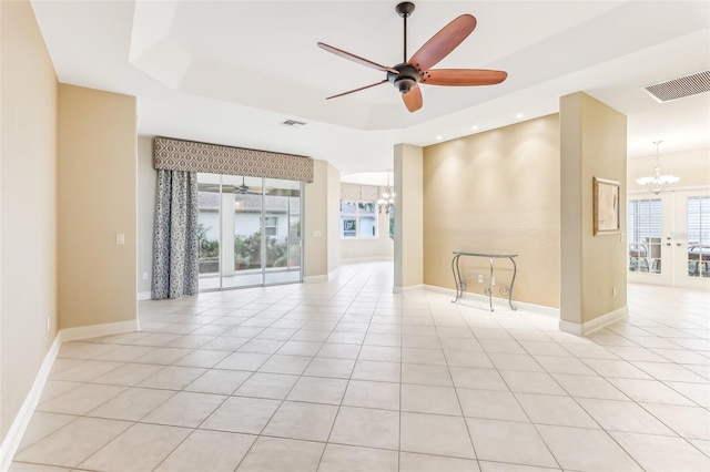 tiled empty room with french doors, a tray ceiling, and ceiling fan with notable chandelier