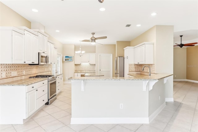 kitchen with light stone counters, white cabinets, kitchen peninsula, and stainless steel appliances