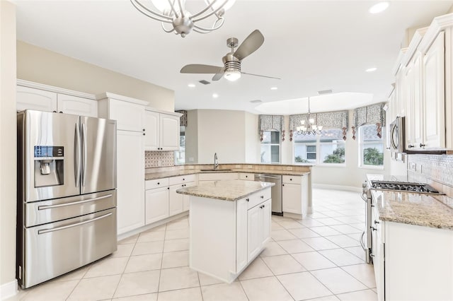 kitchen with light tile patterned floors, a peninsula, appliances with stainless steel finishes, and a sink