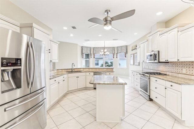 kitchen with a peninsula, a kitchen island, a sink, appliances with stainless steel finishes, and decorative backsplash