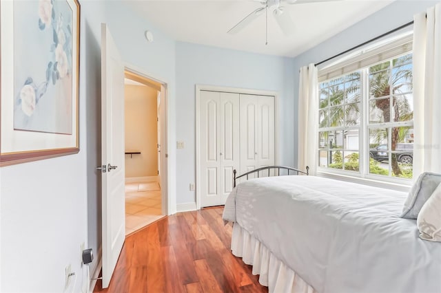 bedroom featuring a ceiling fan, a closet, baseboards, and wood finished floors