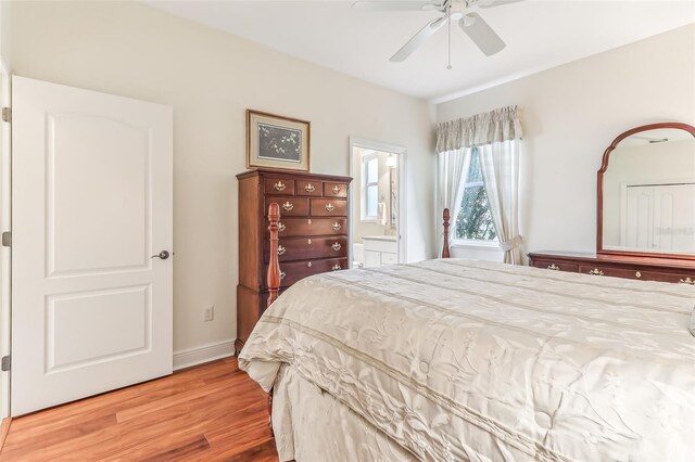 bedroom featuring ceiling fan, ensuite bath, and light wood-type flooring