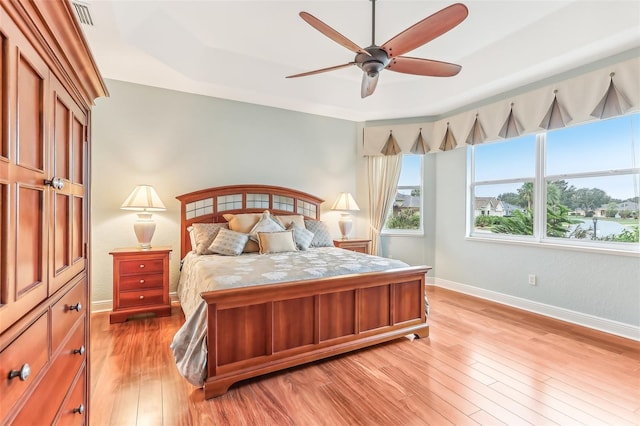 bedroom featuring light wood-type flooring, visible vents, baseboards, and a ceiling fan