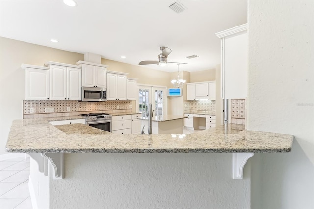 kitchen with a breakfast bar, stainless steel appliances, visible vents, decorative backsplash, and light tile patterned flooring