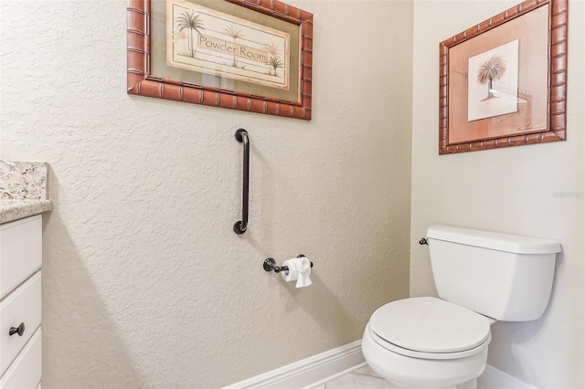 bathroom with toilet, a textured wall, vanity, and baseboards