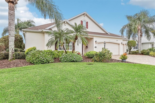 mediterranean / spanish house featuring a garage, a front lawn, decorative driveway, and stucco siding