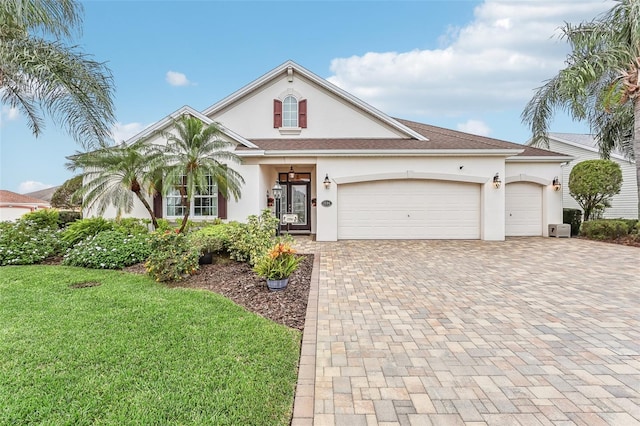 view of front of house featuring an attached garage, a front lawn, decorative driveway, and stucco siding