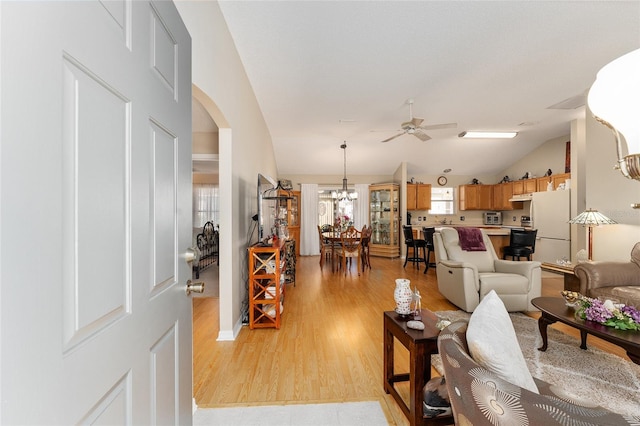 living room featuring light hardwood / wood-style floors, lofted ceiling, and ceiling fan with notable chandelier