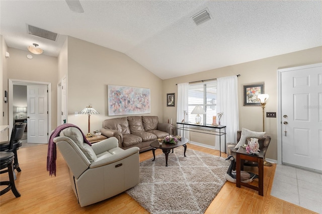 living room featuring a textured ceiling, lofted ceiling, and light hardwood / wood-style flooring