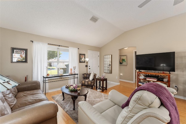 living room featuring light hardwood / wood-style floors, lofted ceiling, a textured ceiling, and ceiling fan