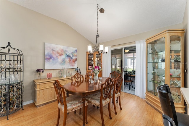 dining space with light hardwood / wood-style floors, a notable chandelier, and lofted ceiling