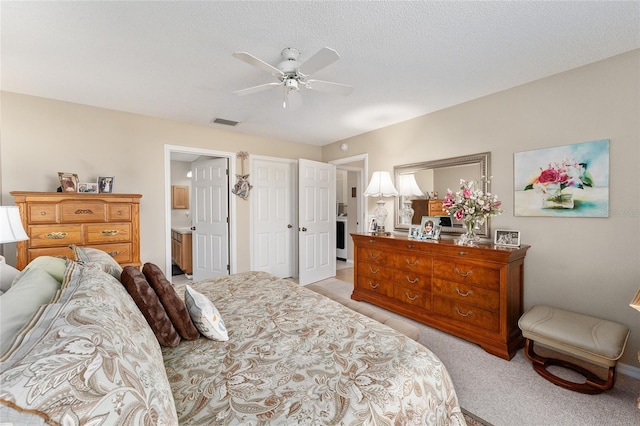 carpeted bedroom featuring ceiling fan, a textured ceiling, and ensuite bath