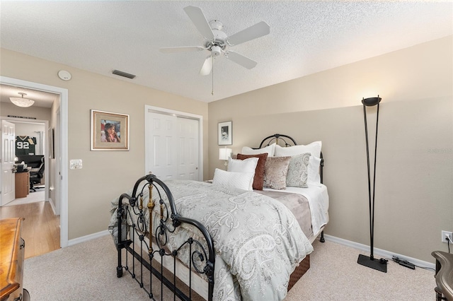 carpeted bedroom featuring a closet, ceiling fan, and a textured ceiling