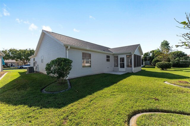 1312 Landeros Ln, The Villages, FL 32159 - rear view of house with a sunroom, a shingled roof, a yard, and cooling unit