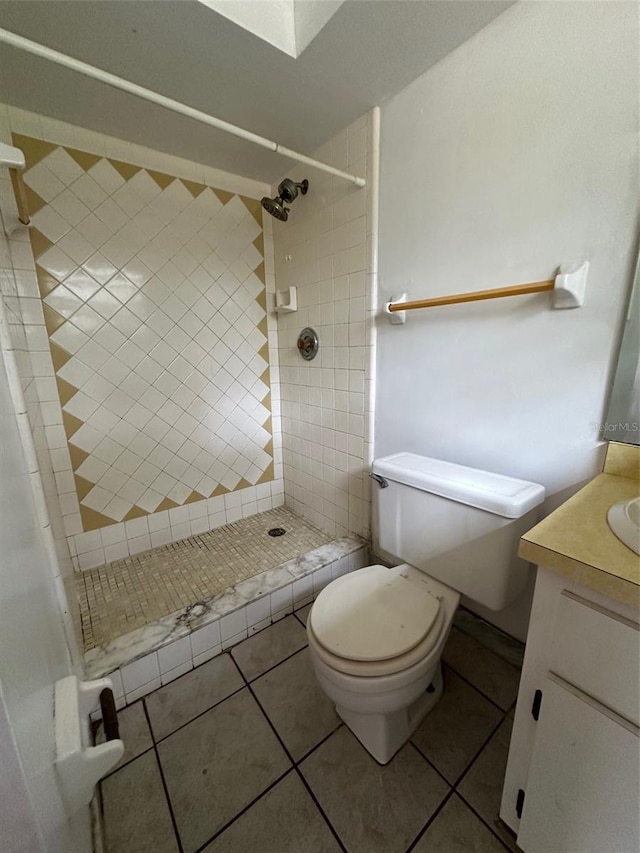 bathroom with vanity, tile patterned floors, a tile shower, and toilet