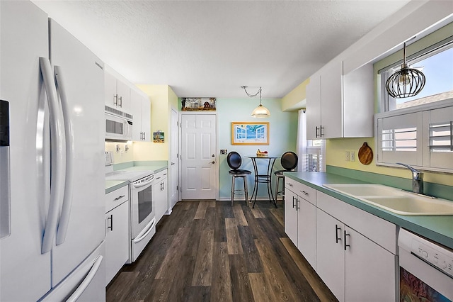 kitchen with white cabinets, sink, hanging light fixtures, and white appliances