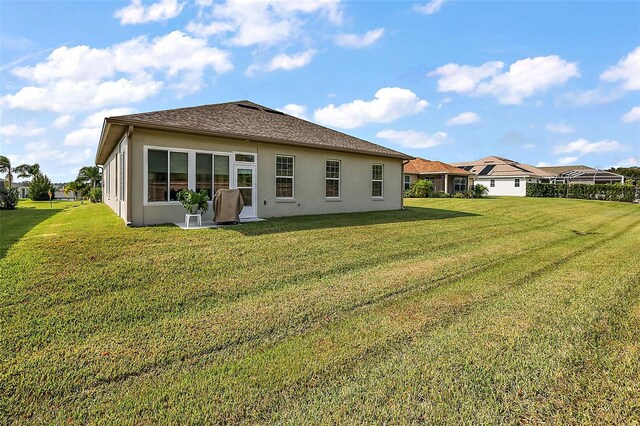 back of property with a lawn and stucco siding