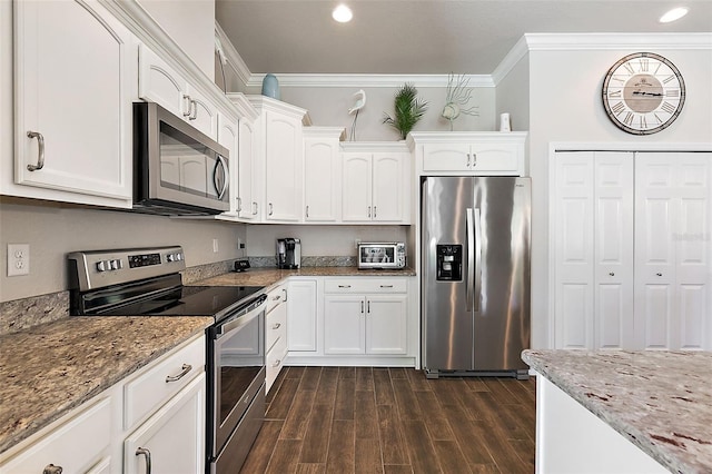 kitchen with appliances with stainless steel finishes, white cabinetry, dark wood-type flooring, crown molding, and light stone counters