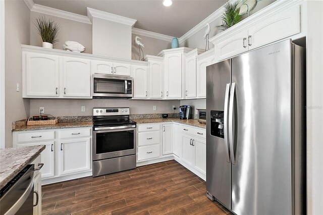 kitchen with white cabinetry, appliances with stainless steel finishes, ornamental molding, and light stone counters