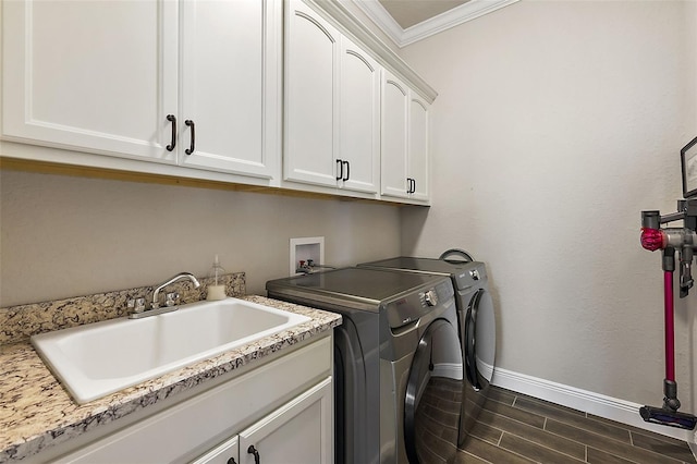 laundry room with sink, dark hardwood / wood-style flooring, washing machine and clothes dryer, crown molding, and cabinets