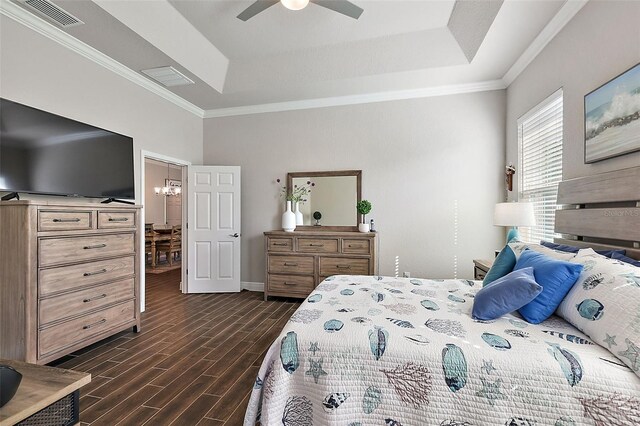 bedroom with a tray ceiling, visible vents, ornamental molding, and dark wood-type flooring