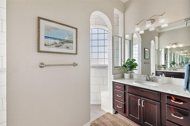 bathroom featuring vanity, crown molding, walk in shower, and wood finished floors