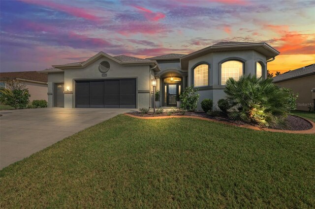 mediterranean / spanish home with an attached garage, stucco siding, driveway, and a front yard