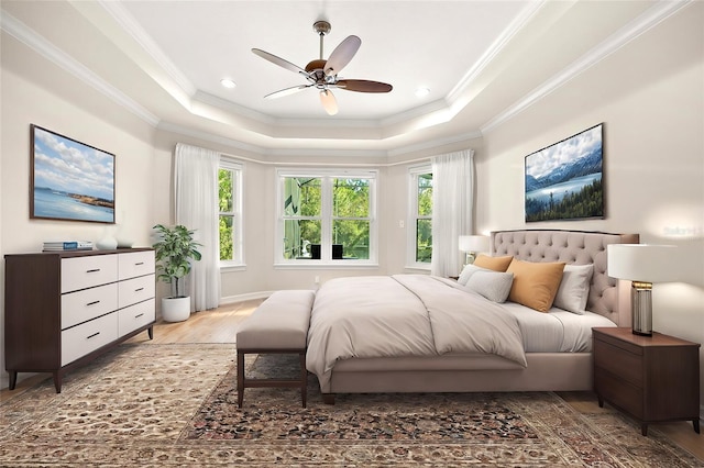 bedroom featuring ceiling fan, wood-type flooring, a tray ceiling, and multiple windows