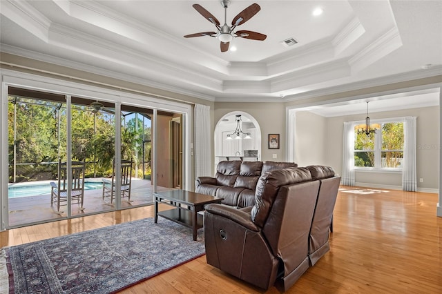 living room with ornamental molding, a raised ceiling, and light hardwood / wood-style floors