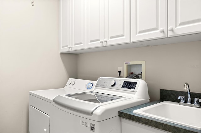 clothes washing area featuring sink, washing machine and dryer, and cabinets