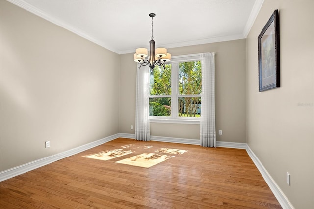 empty room featuring a notable chandelier, crown molding, light wood-type flooring, and baseboards