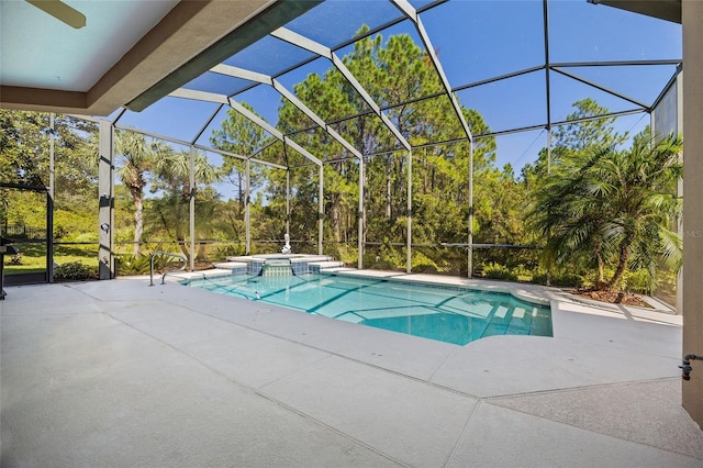 view of pool with a patio area, glass enclosure, and a pool with connected hot tub