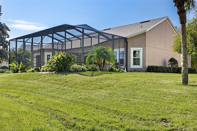 rear view of house with stucco siding, a lawn, and a lanai