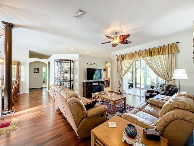 living room with ceiling fan, wood-type flooring, a textured ceiling, and decorative columns