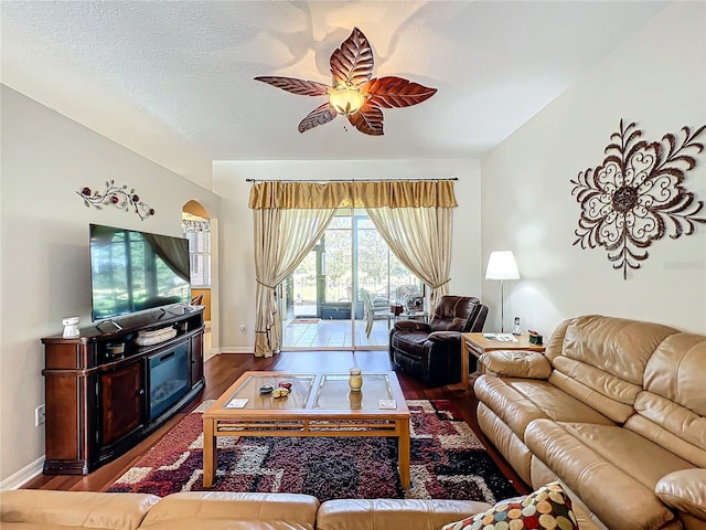 living room with wood-type flooring, ceiling fan, and a textured ceiling