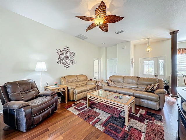 living room featuring ornate columns, hardwood / wood-style floors, ceiling fan, and a textured ceiling