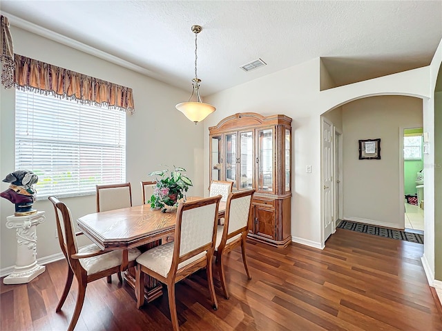 dining room with a textured ceiling and dark hardwood / wood-style floors