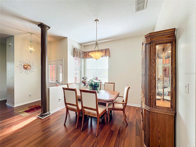 dining room featuring dark wood-type flooring, a textured ceiling, and decorative columns