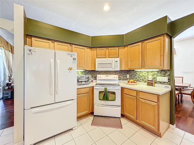 kitchen with white appliances, a textured ceiling, light wood-type flooring, and tasteful backsplash