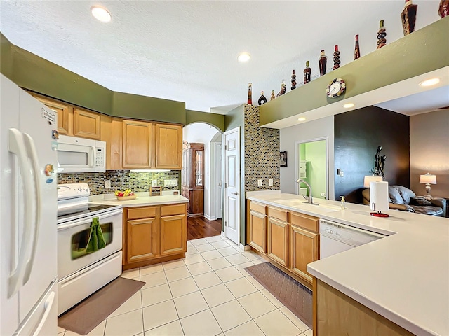 kitchen featuring decorative backsplash, kitchen peninsula, light tile patterned flooring, and white appliances